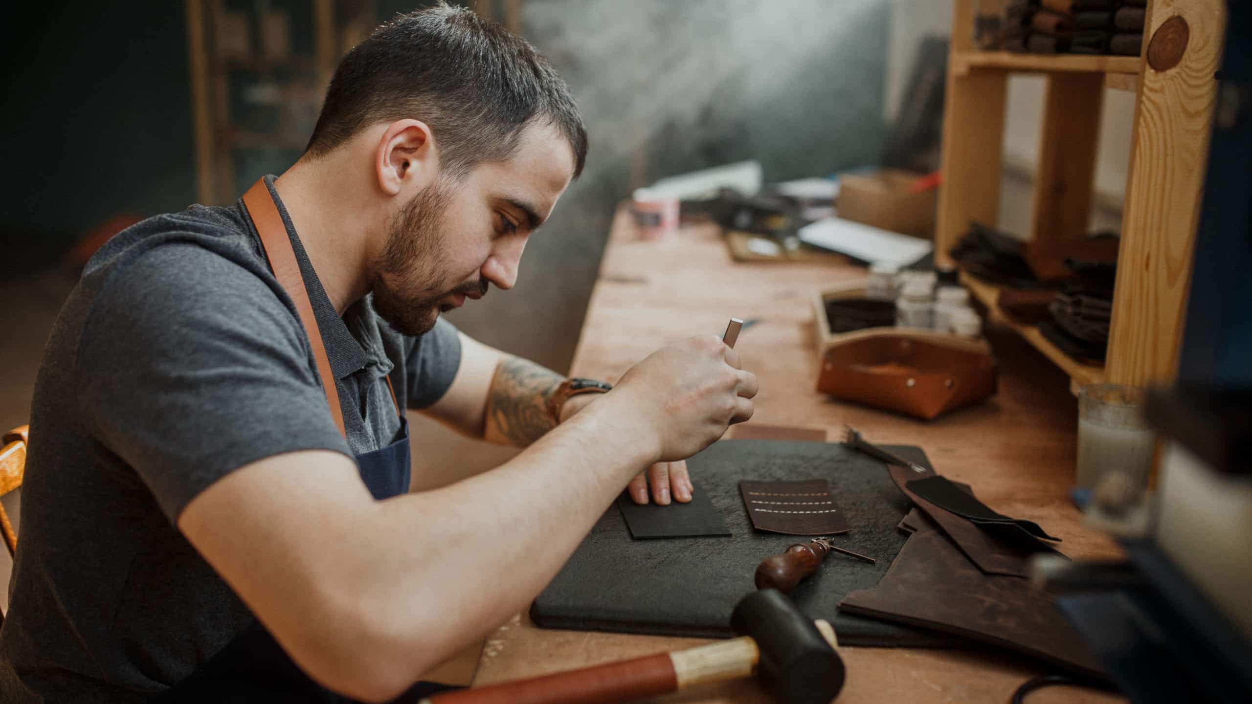 Maroquinier qui utilise des accessoires pour coller du cuir